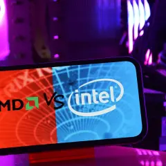 Telefon z logo AMD vs Intel na tle podświetlonego komputera. Który procesor intel czy amd wybierzesz?