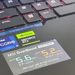 Naklejki Intel Core i9 i NVIDIA GeForce RTX na laptopie z podświetlaną klawiaturą, sugerujące wysoki ranking kart graficznych i wydajność procesora.