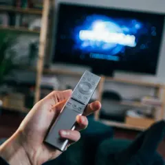 Dłoń trzyma pilota do telewizora, na ekranie logo Universal. Czas na seans filmowy z DVB-T.