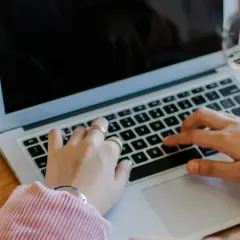 Kobieta pisze na laptopie. Obok leży telefon i notatnik. To jest print screen z jej pracy.
