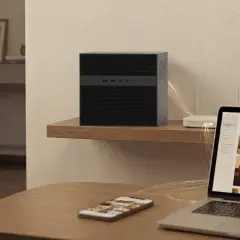 Elegancki serwer domowy na półce, podłączony do routera. Obok laptop z galeriami zdjęć i telefon.