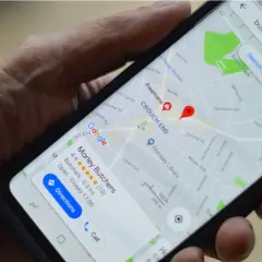 Dłoń trzyma smartfon z widoczną mapą Google. Wyszukiwanie "butcher" pokazuje lokalizację "Morley Butchers". Przydatne mapy Google offline.