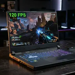 Laptop z podświetlaną klawiaturą gra w grę akcji przy 120 FPS. W tle widać półki z figurkami. Intel UHD Graphics zapewnia płynną rozgrywkę.