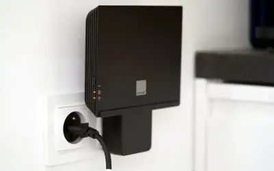 Czarny router Orange Funbox 6 podłączony do gniazdka.