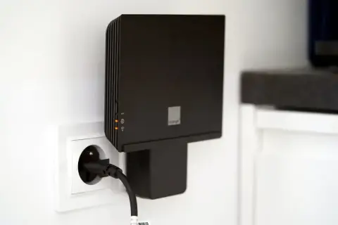 Czarny router Orange Funbox 6 podłączony do gniazdka.