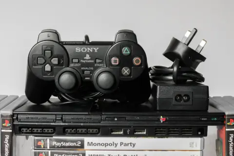 Konsola PlayStation 2 z kontrolerem DualShock 2, zasilaczem i grami. Klasyczny emulator PS2, gotowy do akcji.