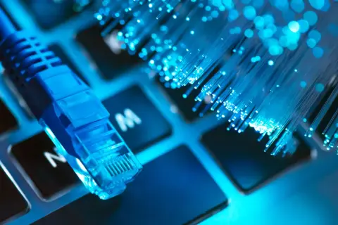 Niebieski kabel sieciowy i światłowody na klawiaturze symbolizują najlepszy internet.