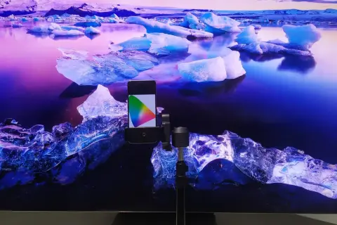 Telefon z kolorowym wzornikiem na tle lodowca, przygotowanie do kalibracji telewizora.