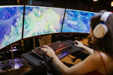 Graczka w słuchawkach gra w grę na trzech monitorach. Nagle pojawia się komunikat o awarii Steam, przerywając rozgrywkę.