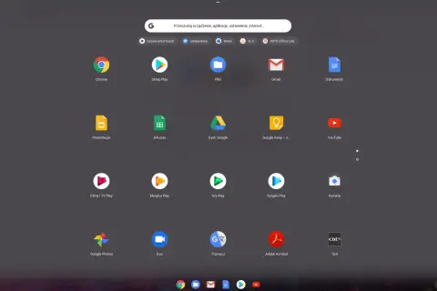 Ekran startowy systemu ChromeOS z ikonami aplikacji: Chrome, Sklep Play, Pliki, Gmail, Dokumenty, Prezentacje, Arkusze, Dysk Google, YouTube, Filmy i TV Play, Muzyka Play, Gry Play, Książki Play, Kamera, Google Photos, Duo, Tłumacz, Adobe Acrobat, Text.