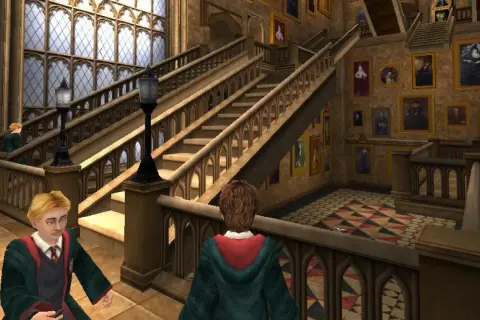Dwóch uczniów w szatach Gryffindoru przemierza korytarz Hogwartu, jak w grach Harry Potter. Obok schodów wiszą ruchome portrety.