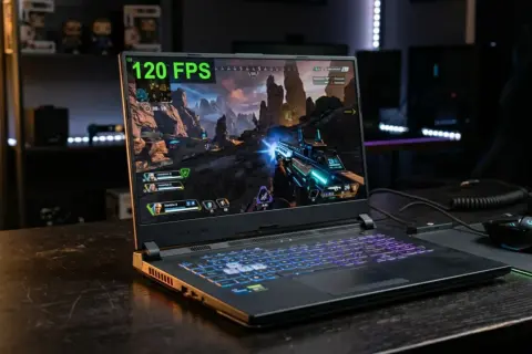 Laptop z podświetlaną klawiaturą gra w grę akcji przy 120 FPS. W tle widać półki z figurkami. Intel UHD Graphics zapewnia płynną rozgrywkę.