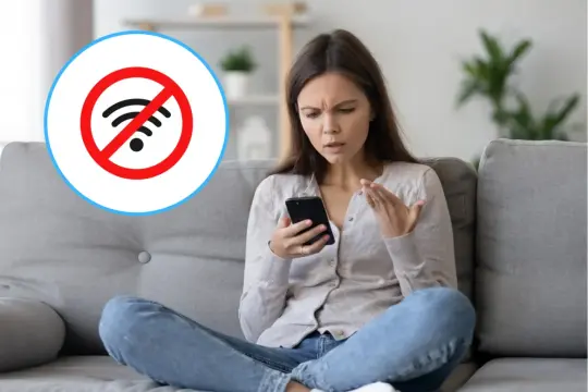 Zirytowana kobieta patrzy na telefon, na którym widnieje symbol braku połączenia z internetem. Jak żyć, gdy wszystko połączono bez internetu?