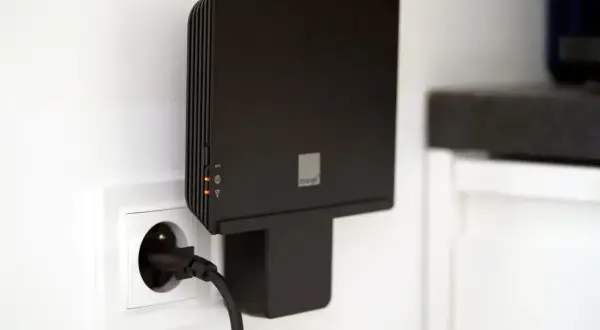 Czarny router Orange Funbox 6 podłączony do gniazdka.