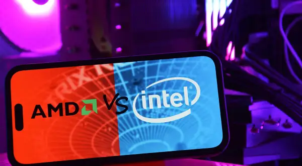 Telefon z logo AMD vs Intel na tle podświetlonego komputera. Który procesor intel czy amd wybierzesz?