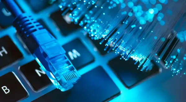 Niebieski kabel sieciowy i światłowody na klawiaturze symbolizują najlepszy internet.