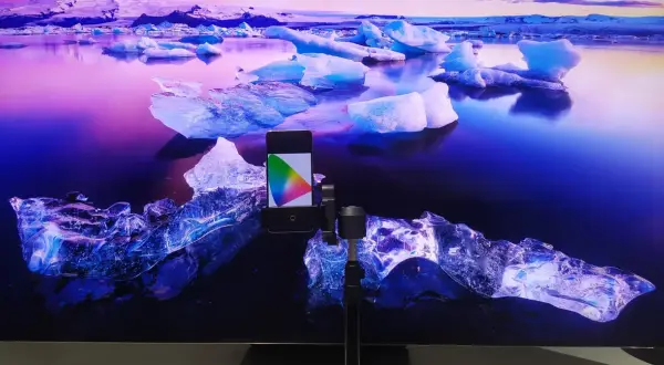 Telefon z kolorowym wzornikiem na tle lodowca, przygotowanie do kalibracji telewizora.
