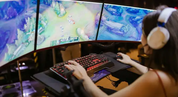 Graczka w słuchawkach gra w grę na trzech monitorach. Nagle pojawia się komunikat o awarii Steam, przerywając rozgrywkę.