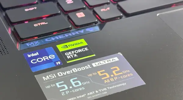 Naklejki Intel Core i9 i NVIDIA GeForce RTX na laptopie z podświetlaną klawiaturą, sugerujące wysoki ranking kart graficznych i wydajność procesora.