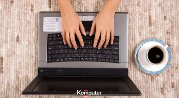 Dłonie piszą na klawiaturze laptopa, obok filiżanka kawy. Stary speccy wciąż działa!