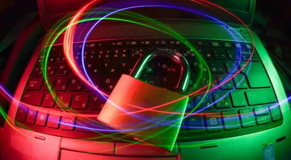 Kłódka na klawiaturze laptopa otoczona kolorowymi światłami, symbolizująca darmowy antywirus na laptopa i bezpieczeństwo danych.