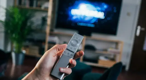 Dłoń trzyma pilota do telewizora, na ekranie logo Universal. Czas na seans filmowy z DVB-T.
