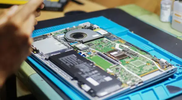 Rozłożony laptop na niebieskiej macie. Widać baterię, wentylator i zieloną płytę główną. Chcesz wiedzieć, jak sprawdzić jaką mam płytę główną?