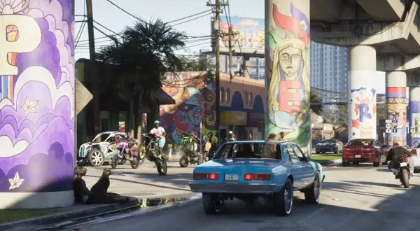 Kolorowe murale zdobią filary wiaduktu. W tle widać ulicę z samochodami i motocyklami, co może sugerować zbliżającą się premierę GTA 6.