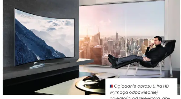 Mężczyzna relaksuje się w fotelu, oglądając krajobraz górski na zakrzywionym ekranie telewizora 16:9. Za nim rozciąga się panorama miasta.
