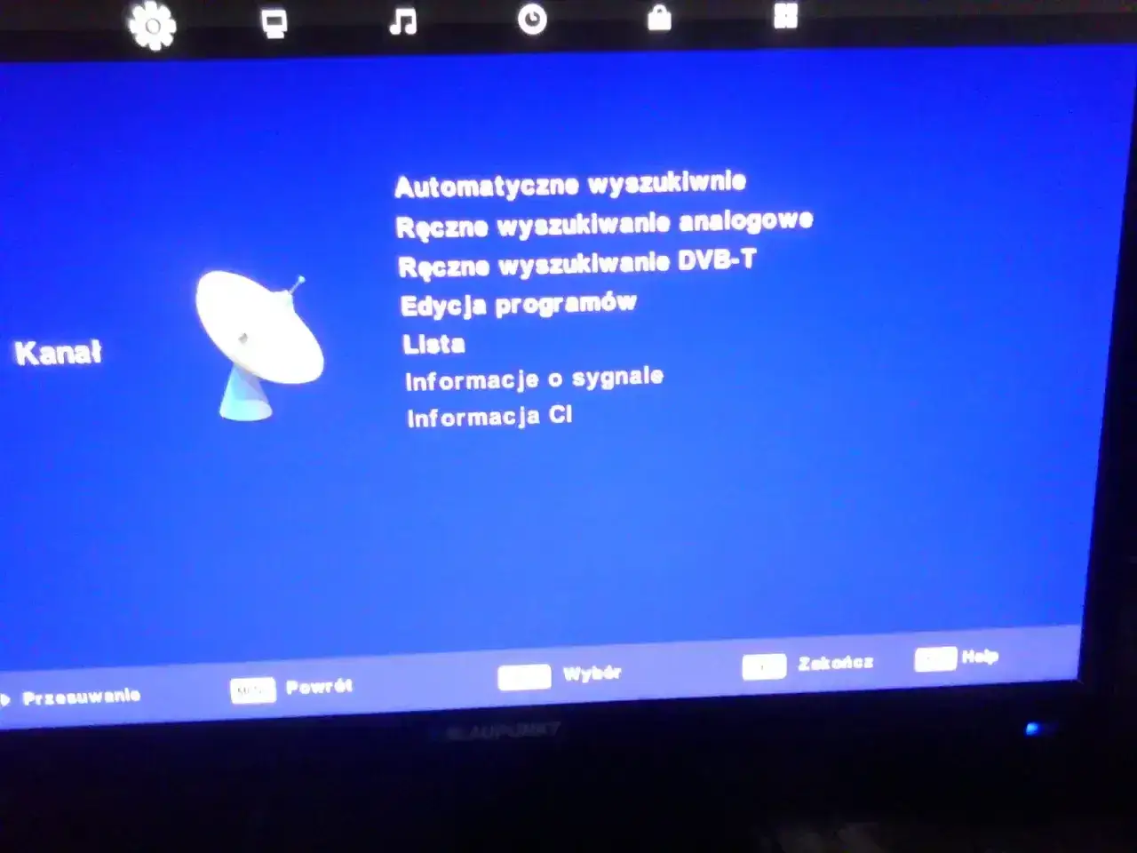 Menu telewizora z opcjami wyszukiwania kanałów, w tym ręczne wyszukiwanie DVB-T. Widoczna antena satelitarna.