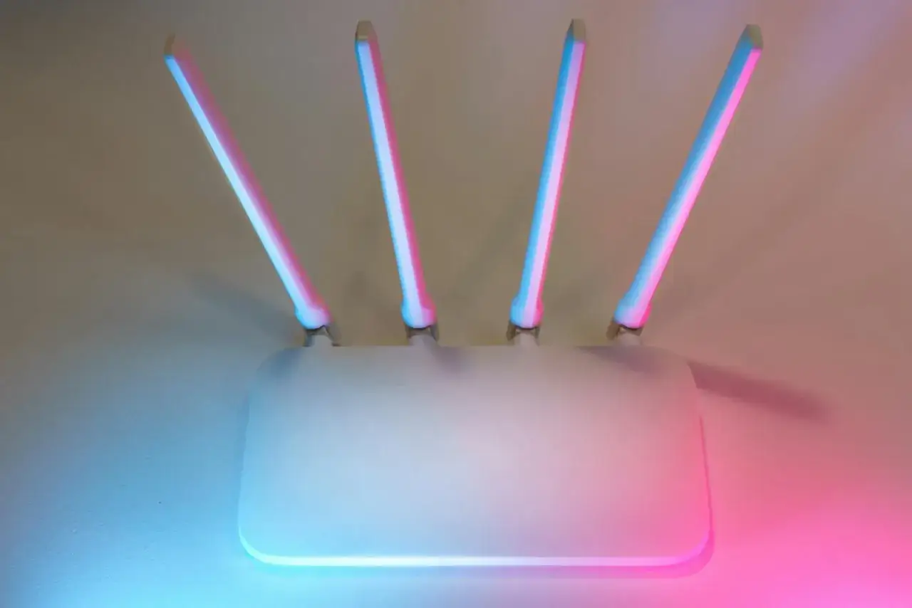 Router z czterema antenkami, podświetlony na różowo i niebiesko. Szybkie połączenie WPS.
