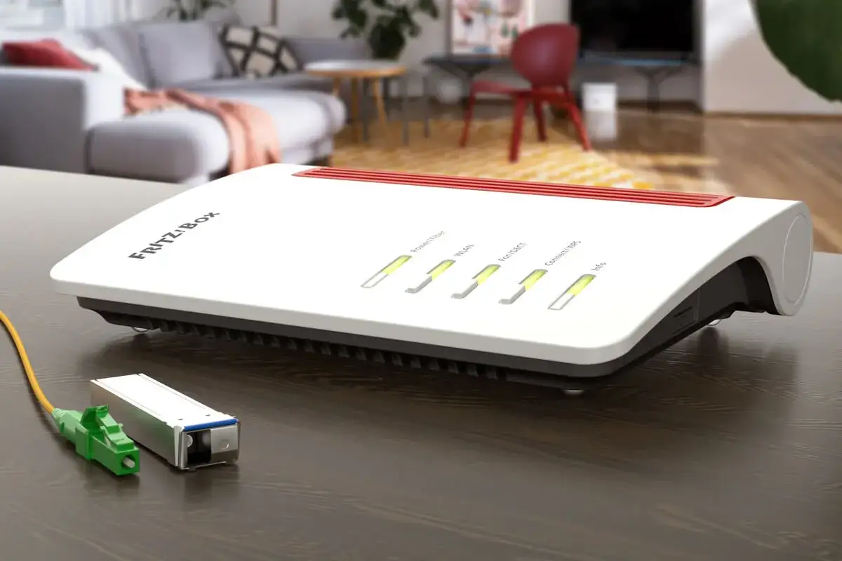 Biały router FRITZ!Box z diodami LED i kablem światłowodowym. Idealny, jeśli zastanawiasz się, jaki router do światłowodu wybrać.