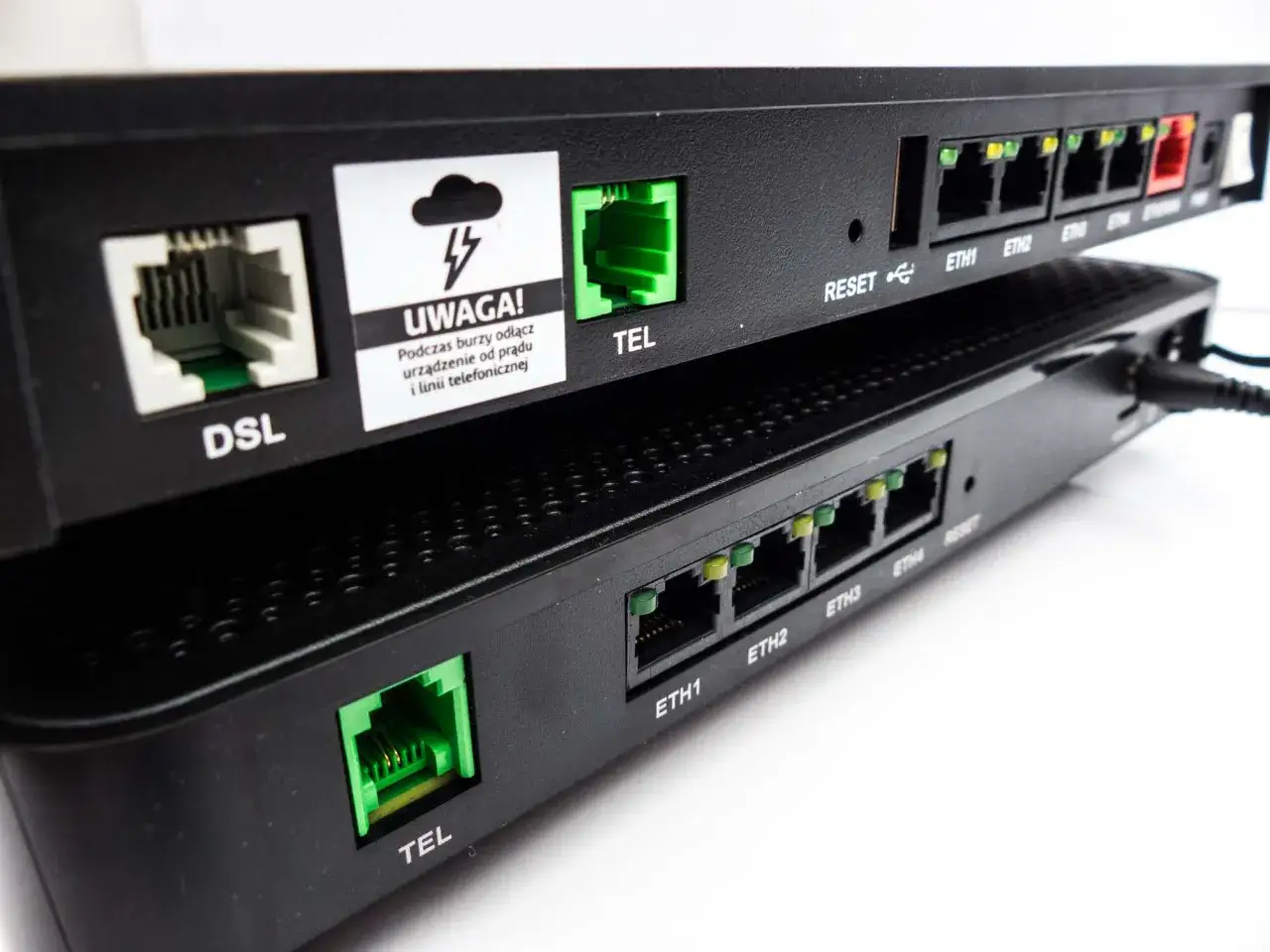 Dwa routery, jeden na drugim. Górny ma oznaczenia DSL, TEL, RESET i porty ETH. Dolny też ma port TEL. To sprzęt sieciowy, może być częścią funbox 3.