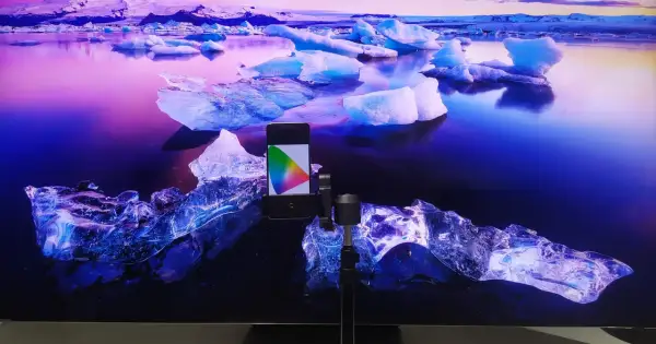 Telefon z kolorowym wzornikiem na tle lodowca, przygotowanie do kalibracji telewizora.