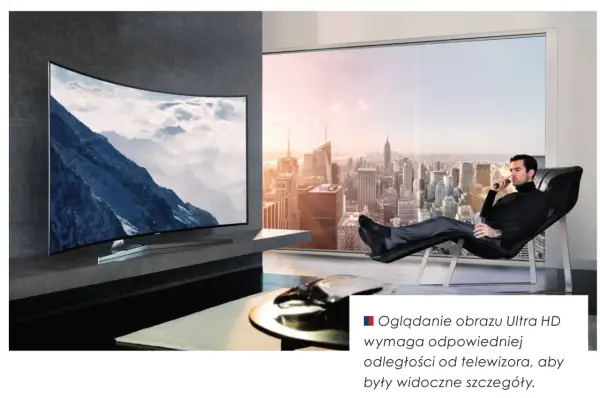 Mężczyzna relaksuje się w fotelu, oglądając krajobraz górski na zakrzywionym ekranie telewizora 16:9. Za nim rozciąga się panorama miasta.